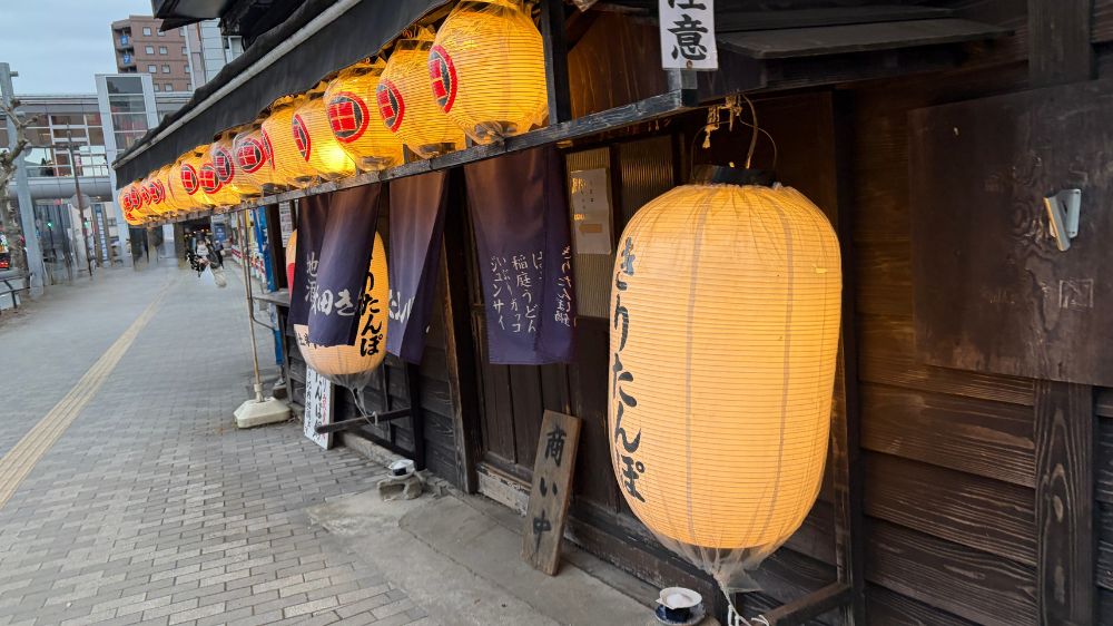 夕方の秋田駅前にあるきりたんぽ屋の外観。提灯が灯り始めた時間帯